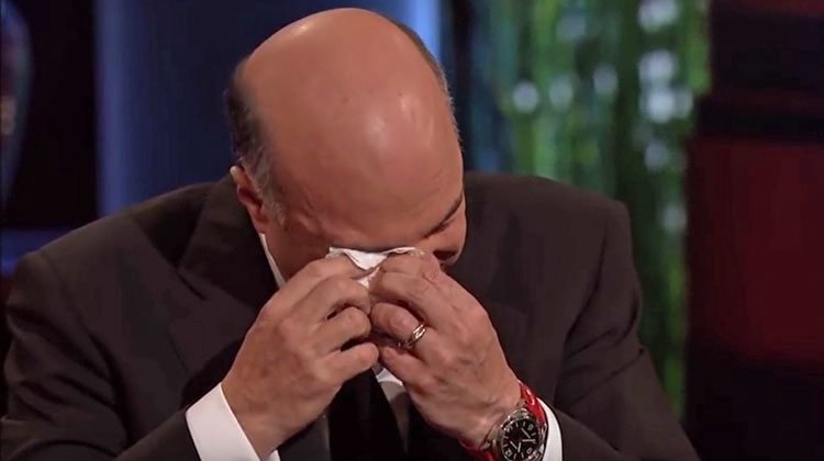 man crying holding tissue to eye