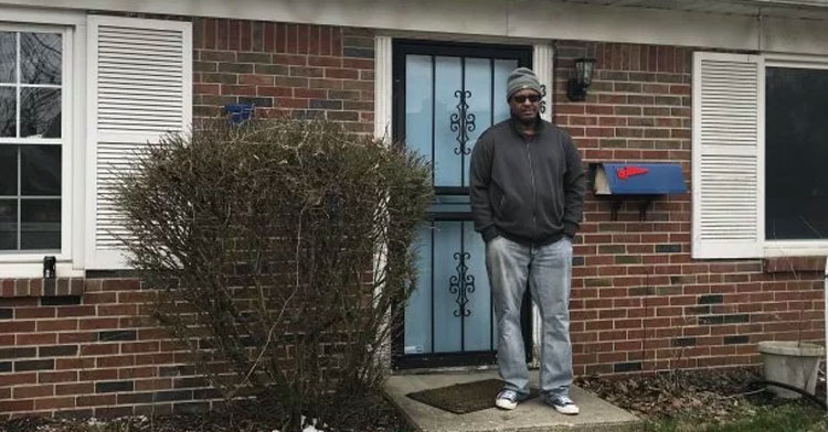 homeless man stands in front of house