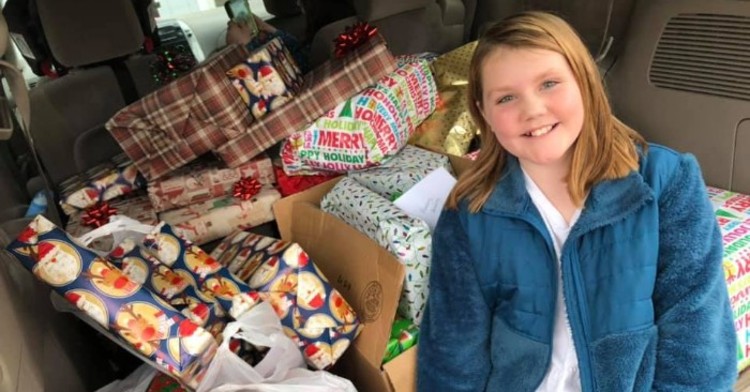 Katy sitting in front of stack of presents for kids