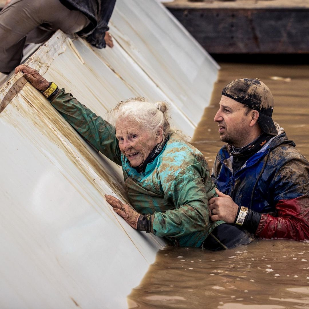 man helps older woman out of the mud
