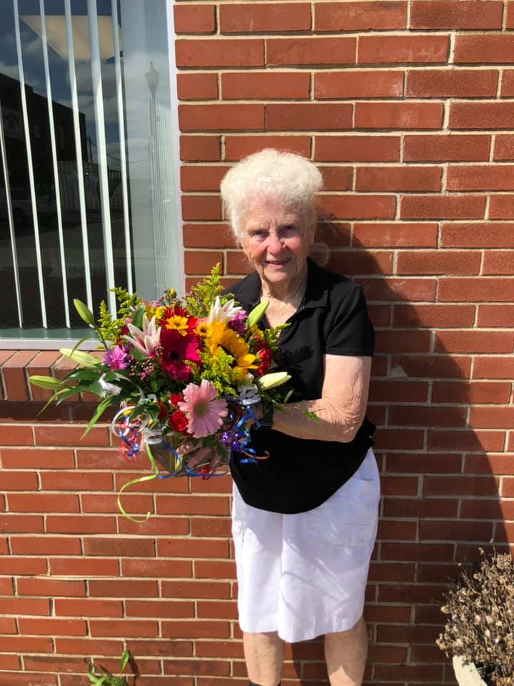 grandma holding flowers outside red brick building