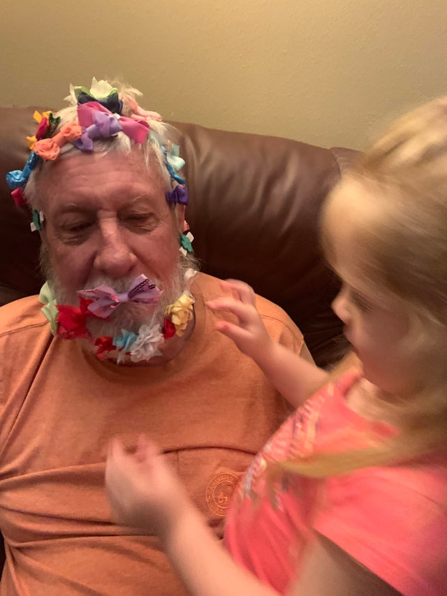 grandpa with a bunch of bows all over his head next to his granddaughter