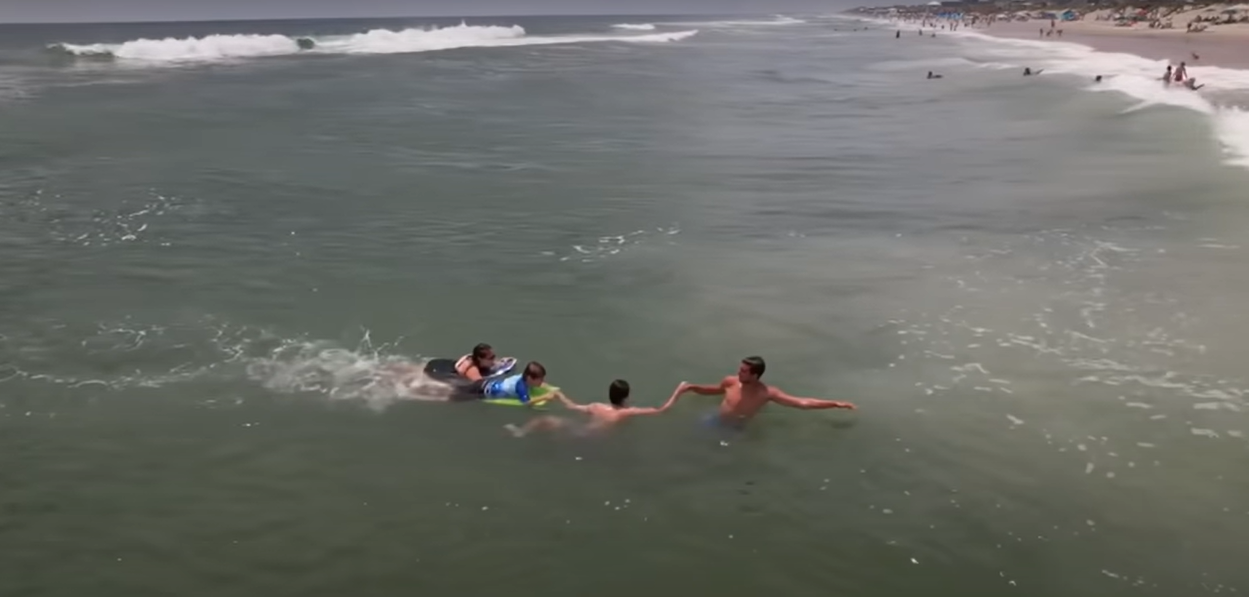 two men pulling mom and son to shore