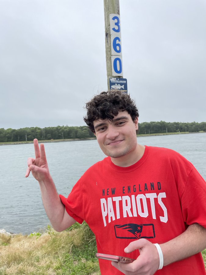 man in red New England Patriots shirt holding up hand with peace sign 