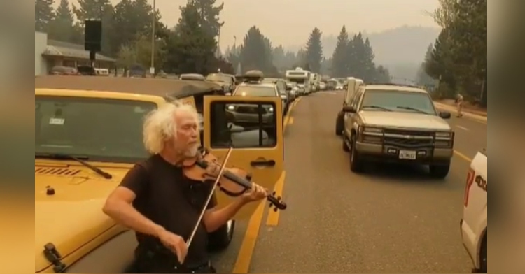 man plays violin on gridlocked highway