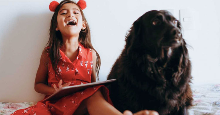 girl laughing next to big dog