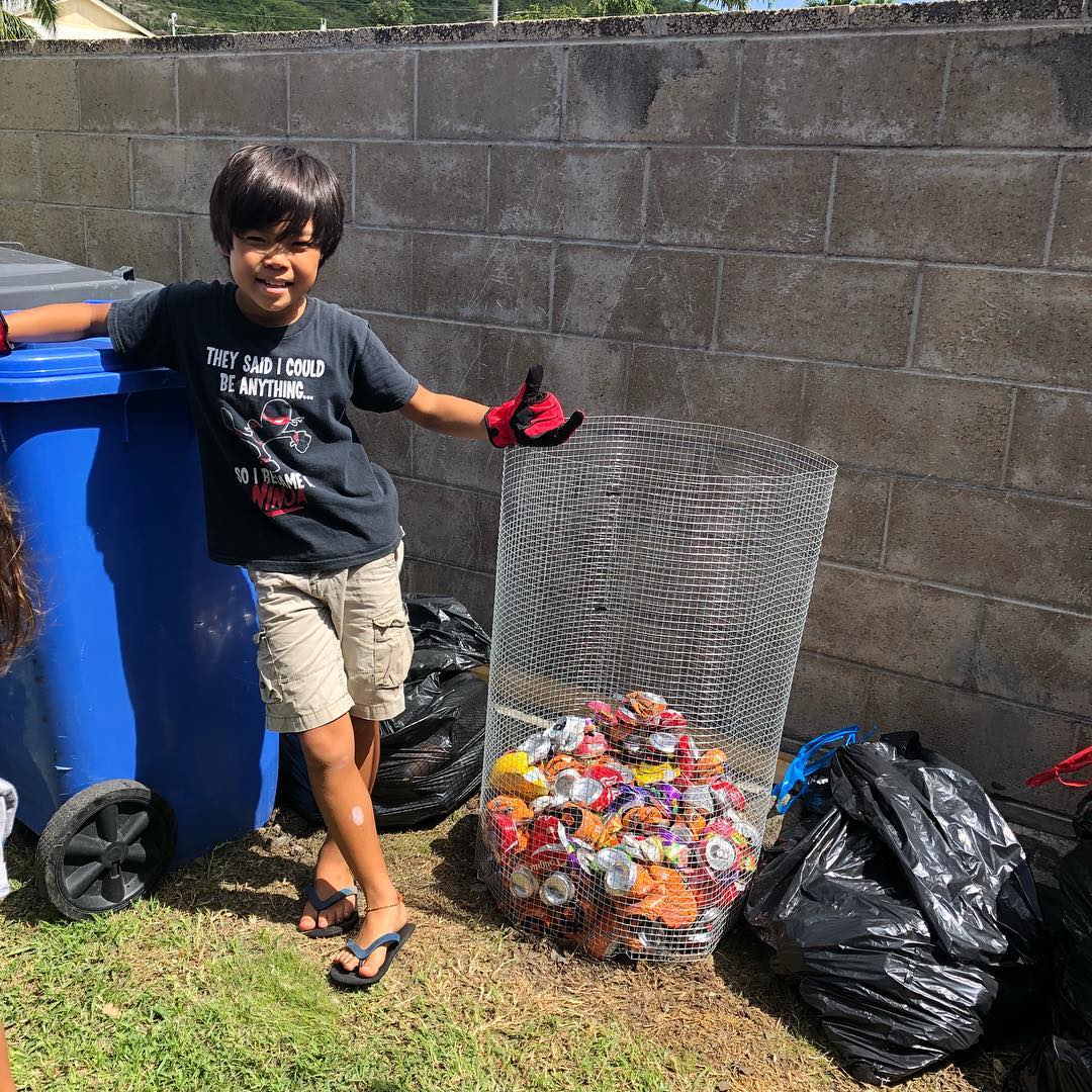 boy smiling next to a recycling container