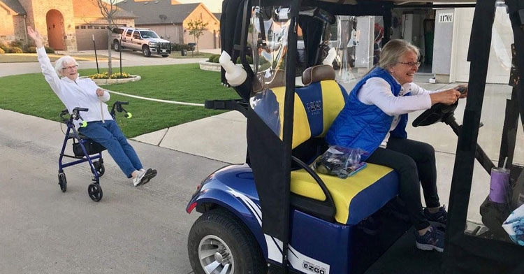 grandma in golf cart pulling grandma on rolling chair behind her
