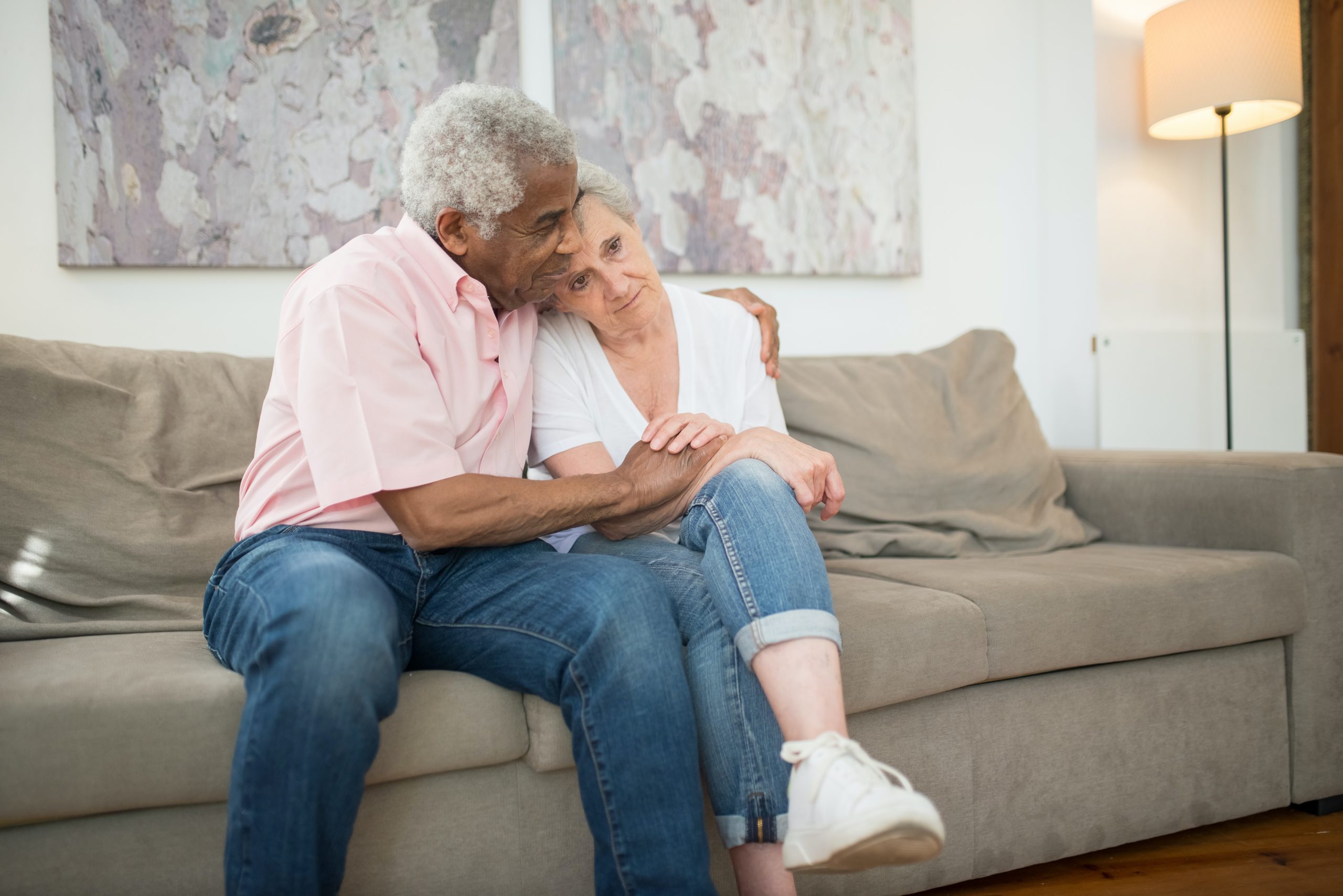 man comforting a woman while they sit on a couch