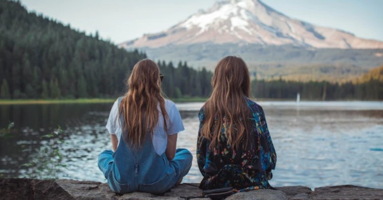 friends sitting in front of lake with their backs turned to camera