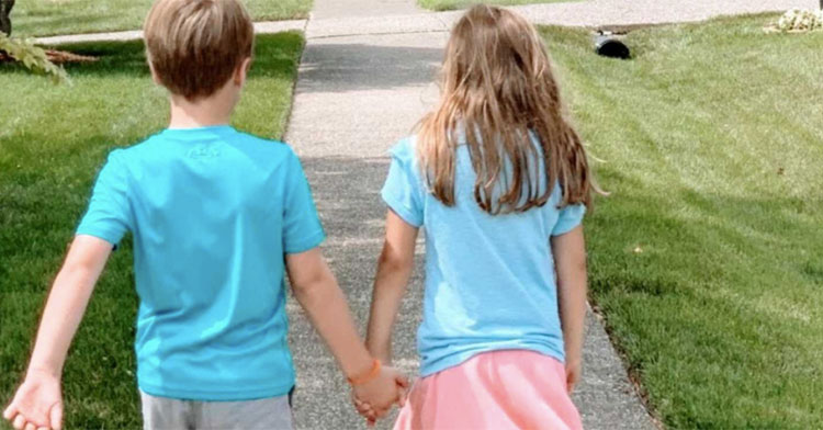little boy in blue shirt holding hands with little girl in blue shirt