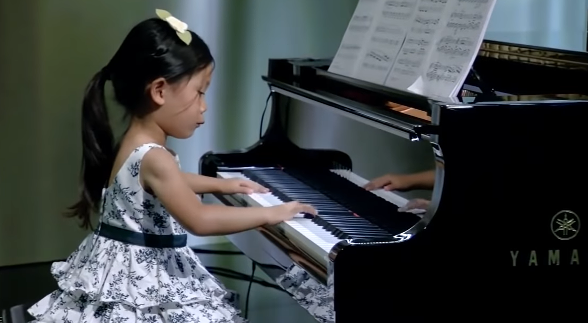 4-year-old playing piano in white and black floral dress