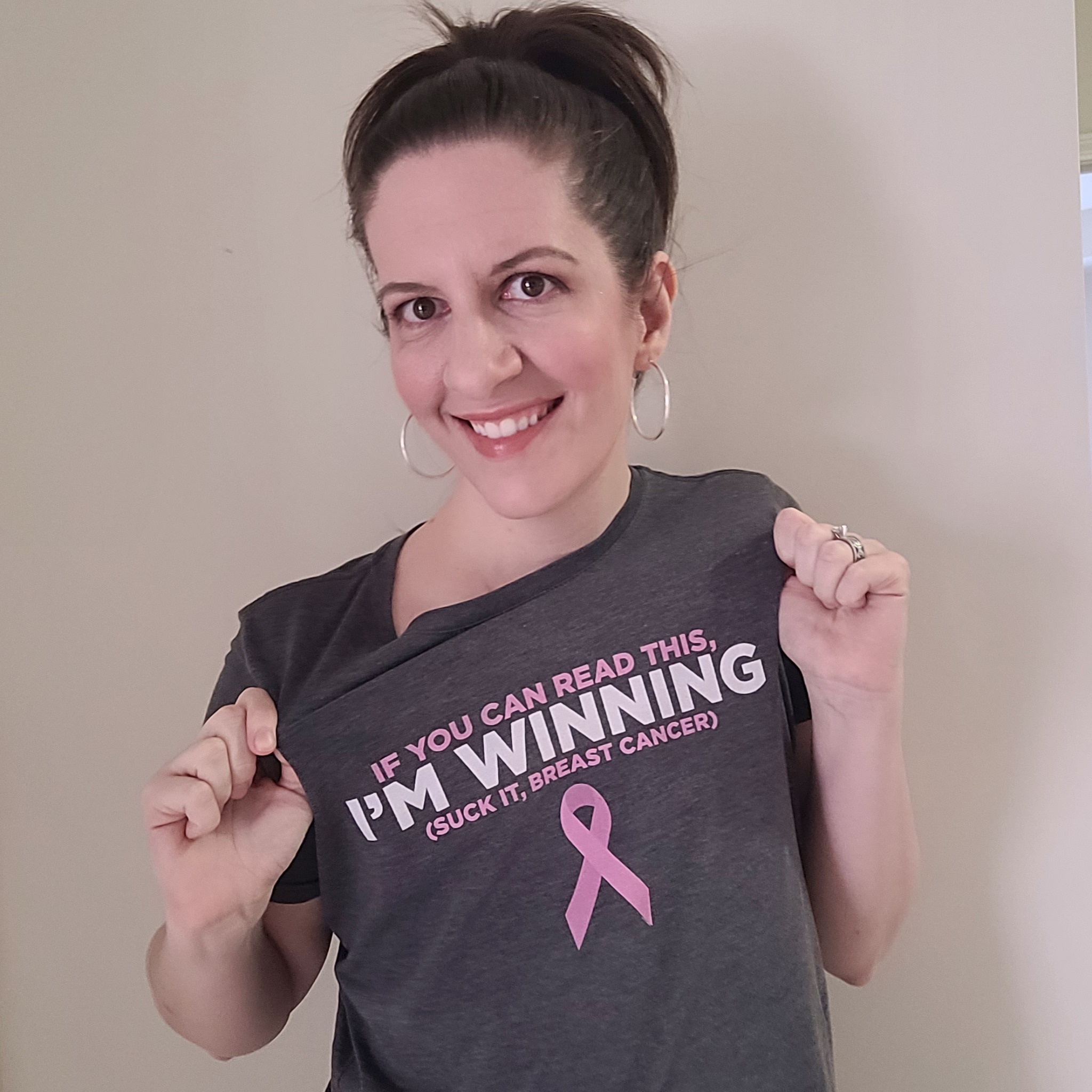 woman wearing shirt that reads "if you can read this, i'm winning (suck it, breast cancer)" 
