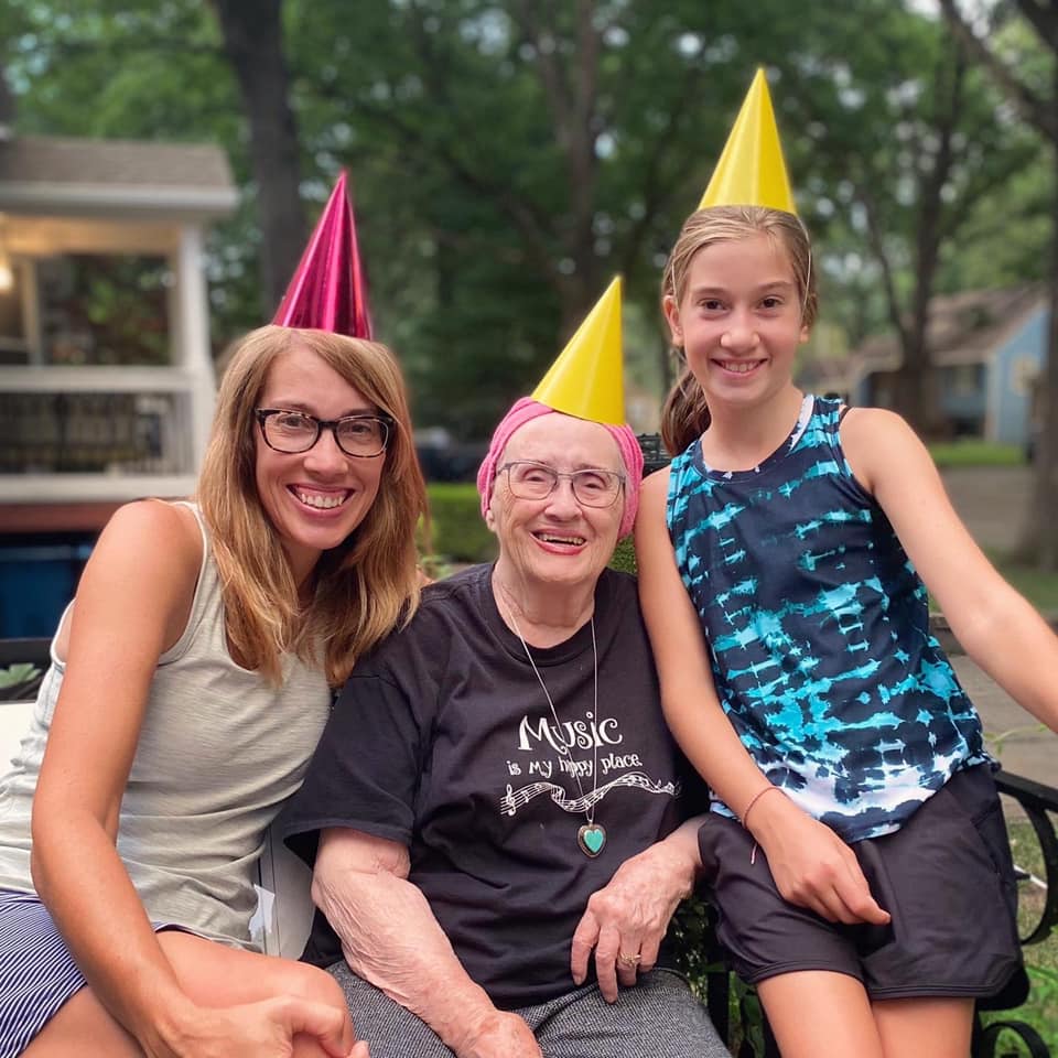 mom and daughter smiling with 93-year-old in party hats