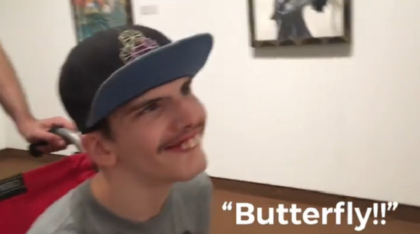 teen with autism smiling in wheelchair at museum and saying "butterfly"