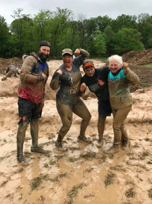 grandma flexing her arm muscle with her tough mudder race team