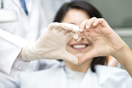 patient forming heart with one of her hands and one of her dentist's