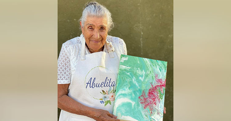 Doña Lupita holding one of her paintings