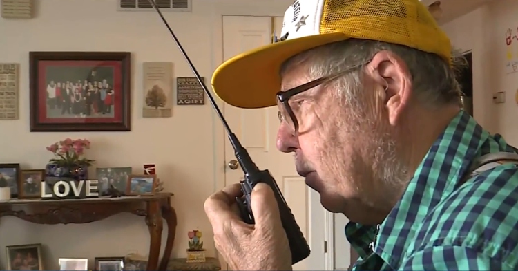 old man using a small black ham radio to talk