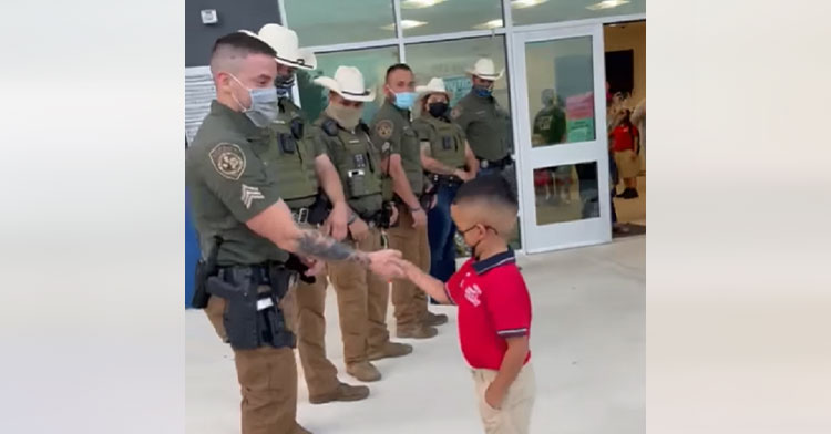 police lined up to shake little boy's hand outside school