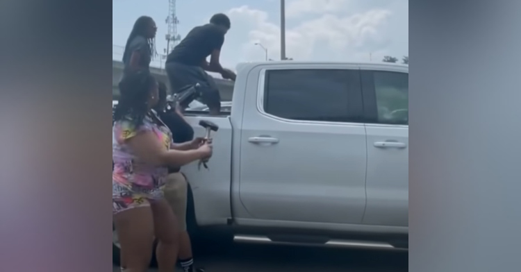 group of people on a white truck trying to break inside to save the driver