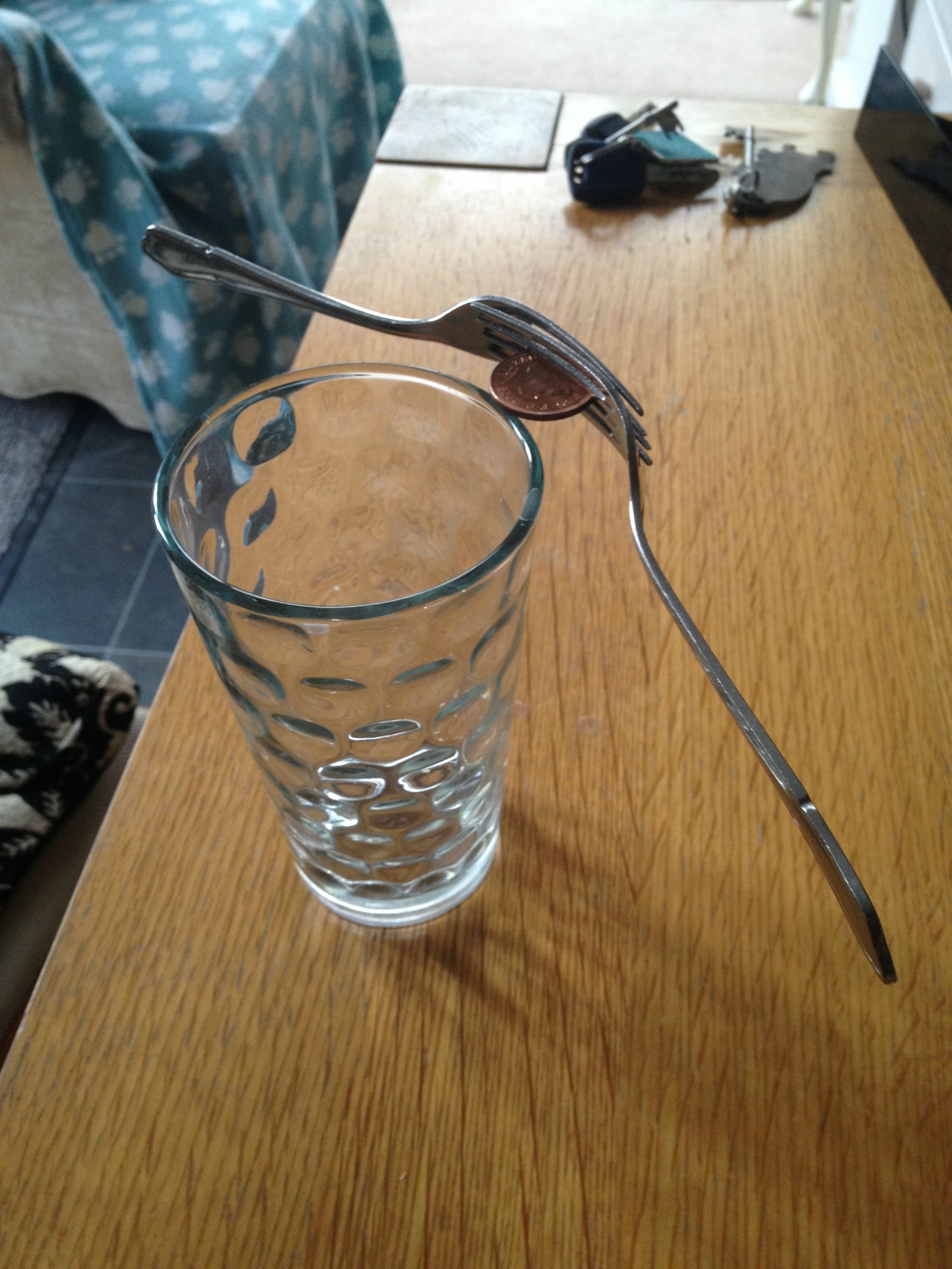 two forks and a penny balanced on a drinking glass
