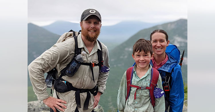 man and woman posing on a mountain with their son
