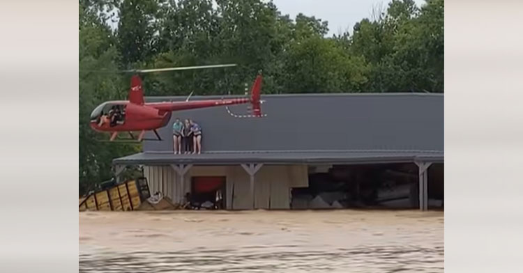 helicopter rescuing three people from roof of flooded home