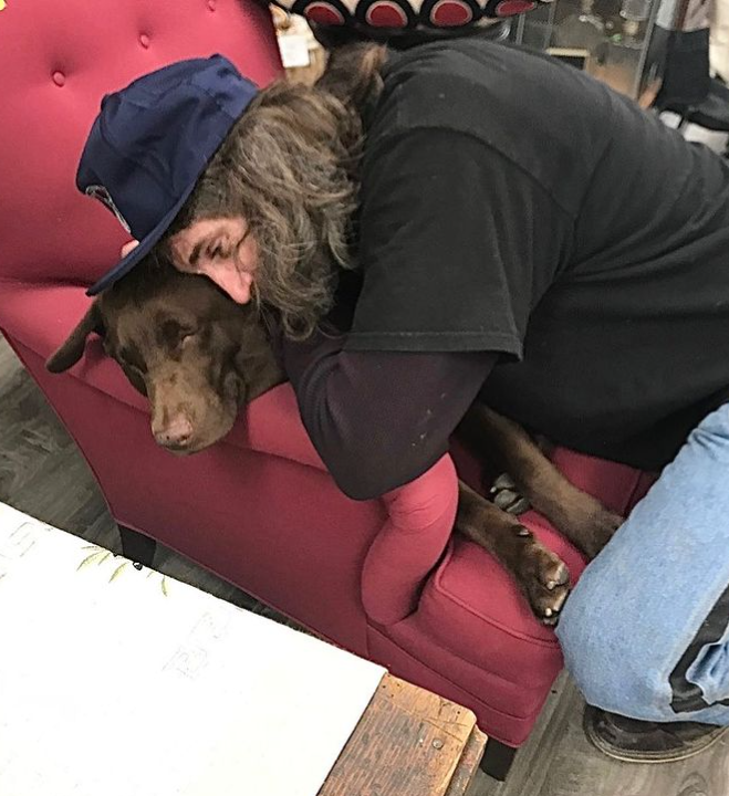 man hugging a dog on top of a red chair