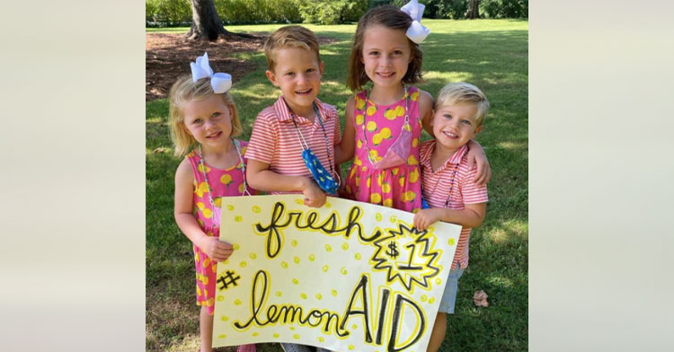 four kids holding sign that reads "lemon-aid"