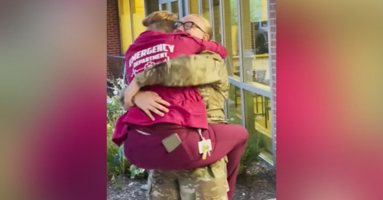 woman in military uniform hugging and holding a healthcare worker who has her legs wrapped around her