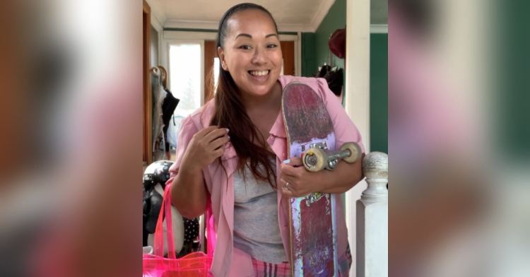 woman holding a skateboard and smiling