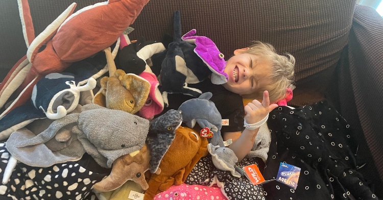 child surrounded by stuffed animals
