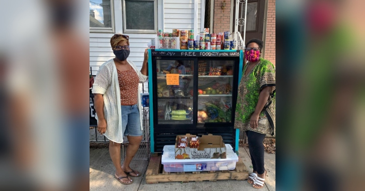 two women standing next to food in giant container