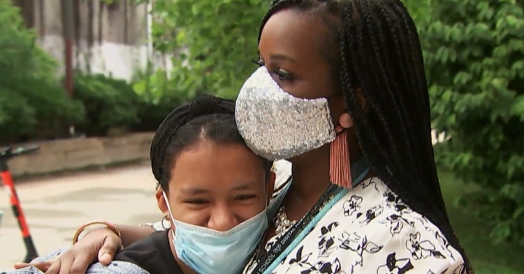 woman wearing a sparkly mask and hugging a high school student who is also wearing a mask