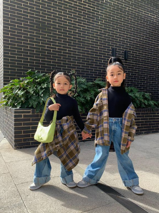 two little girls holding hands outside and posing in front of a brick building