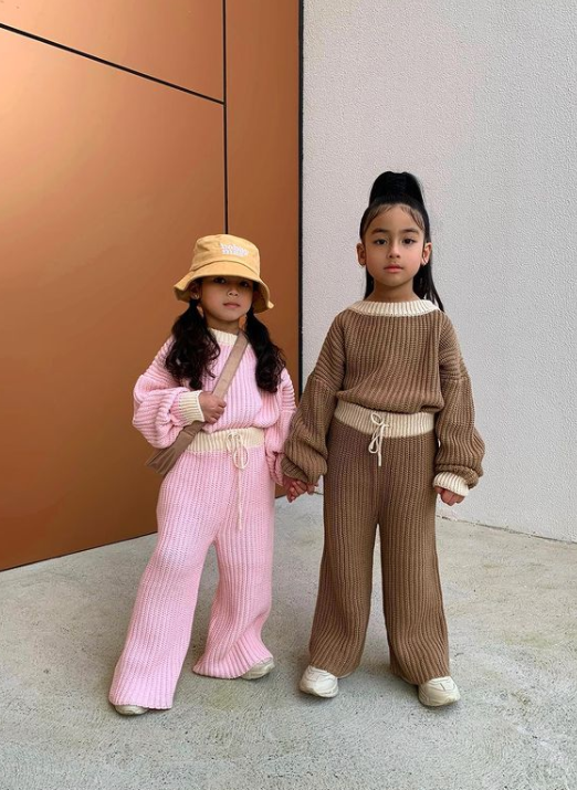 two little girls wearing matching outfits and holding hands