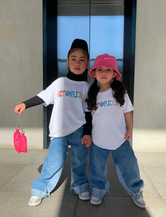 two little girls wearing t-shirts and jeans who are holding hands