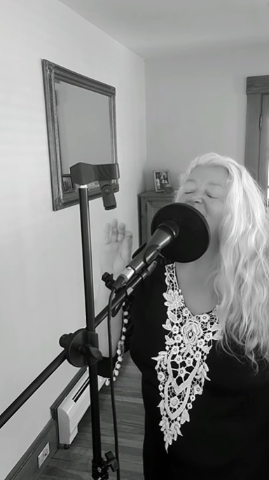 woman passionately singing into a microphone on a stand