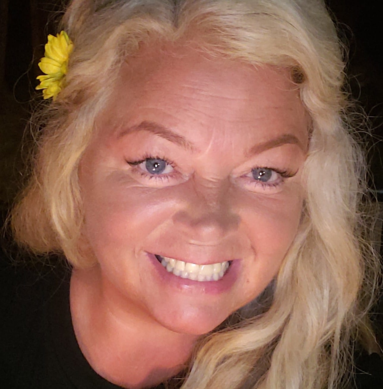woman with yellow flower in her hair smiling