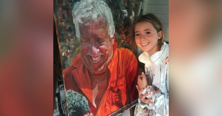 14 year old girl posing and smiling with a portrait of her grandfather