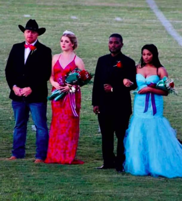 four members of homecoming court standing next to each other on field