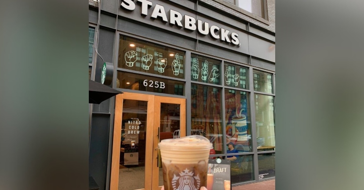 a starbucks drink that someone is holding with the signing store starbucks location in the background