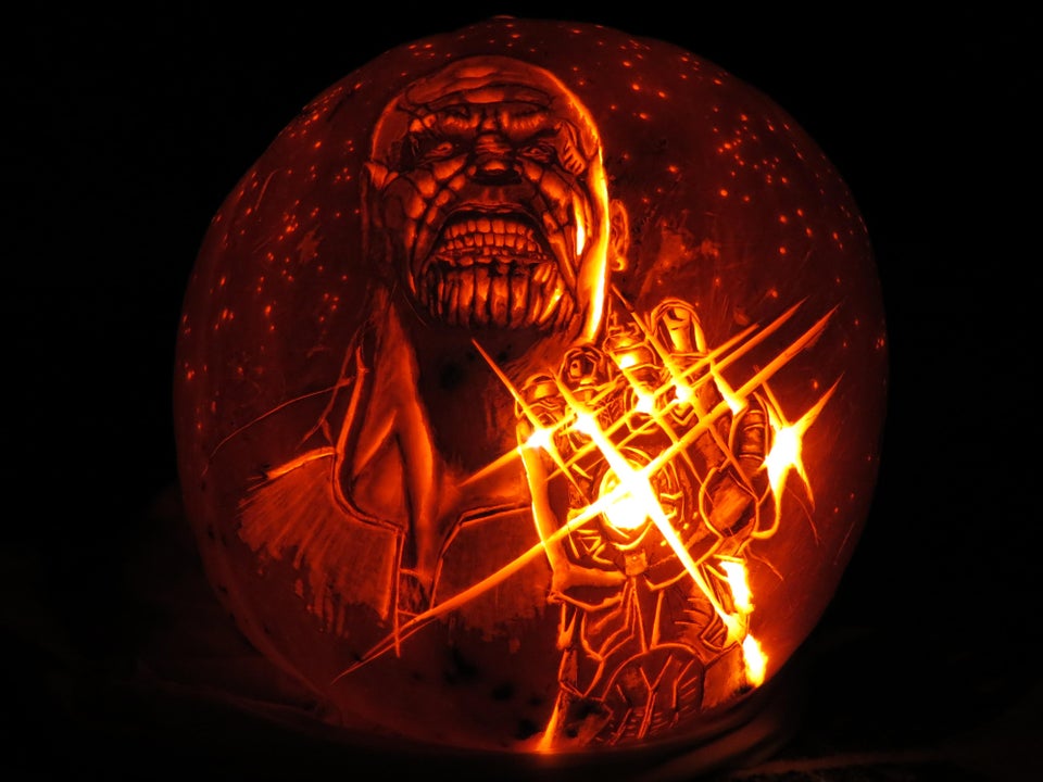 lit up carved pumpkin made to look like thanos from the marvel cinematic universe 