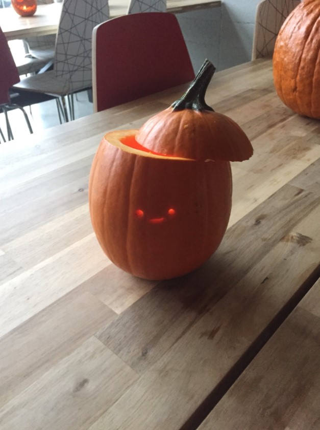 pumpkin carved with a super tiny and basic smiley face with the top part cut off in a way that looks like a hat