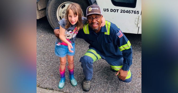 6 year old little girl and a santitation worker smiling and posing in front of a garbage truck