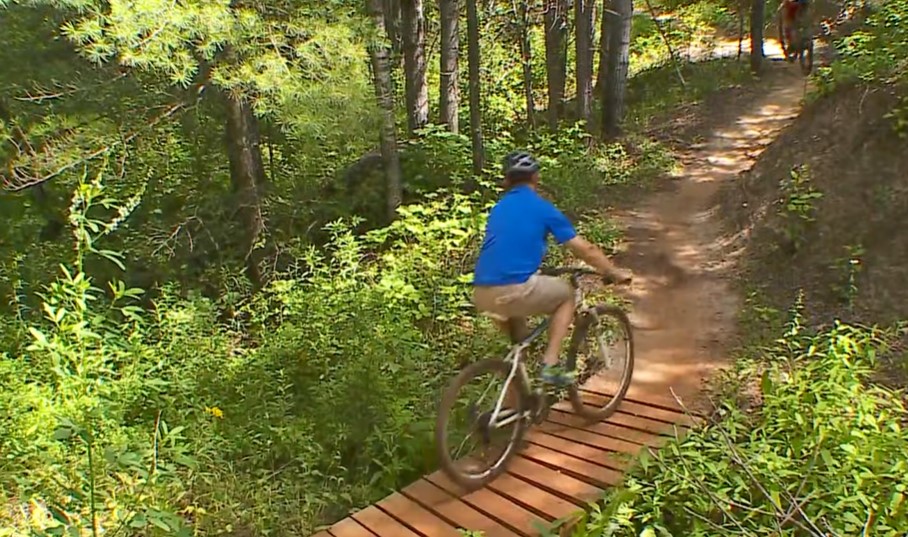 man wearing a blue shirt and a helmet riding a bike along a nature trail
