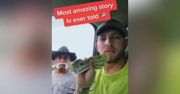 man sitting in a truck and holding money up with a man with a mustache standing next to him