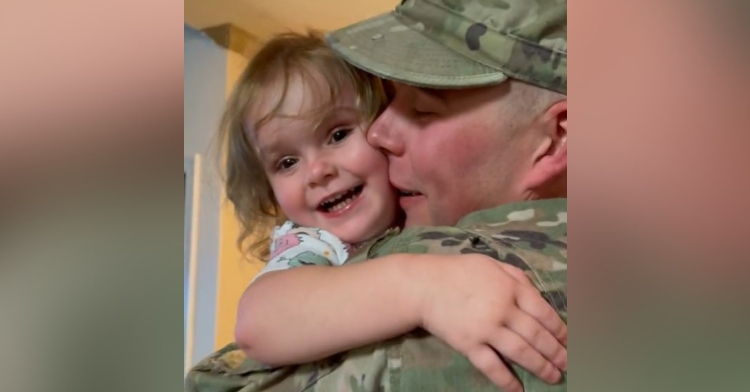 man wearing a military uniform who is holding and hugging a little girl who is smiling