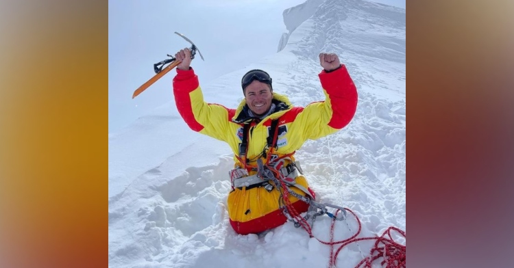 double amputee rustam nabiev smiling with his arms raised in celebration at the top of mount manaslu